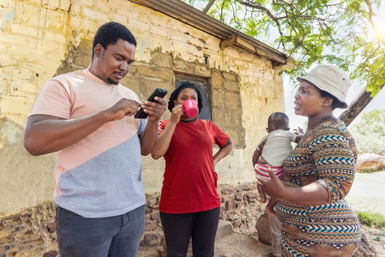 African social worker volunteer with a phone for mobile data collection interviewing villagers in in Botswana.