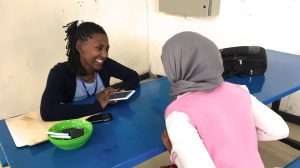 A woman interviews another woman using a mobile device.