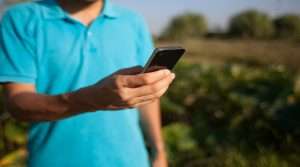 Man in blue shirt holds a mobile device.