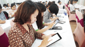 Two women in a conference setting looking at tablets